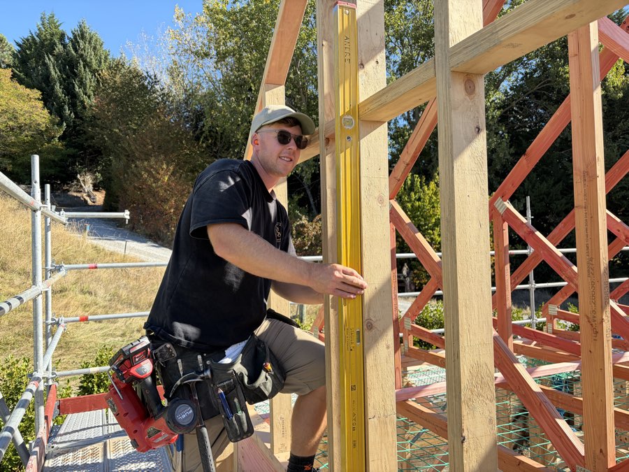 Nick checking a wall frame for plumb with a level on a Project Built site
