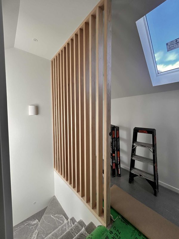Interior timber slat screen beside a stairwell skylight in a renovated home